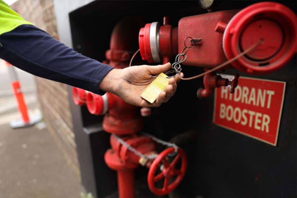 man checking a fire hydrant booster