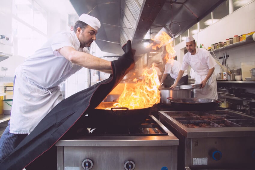 Chef extinguishing a fire with a fire blanket
