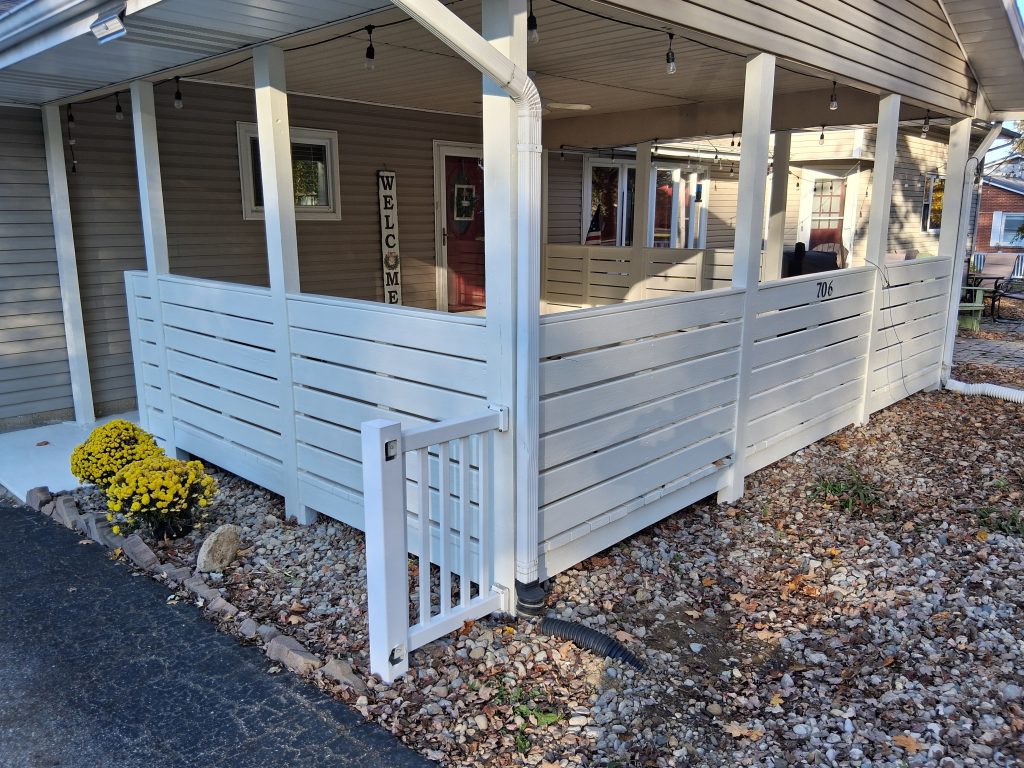 Inviting front porch with white fencing, potted plants, and welcoming decor for a charming home.