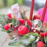 Aranjamente festive de Crăciun cu crenguțe de brad, lumânări roșii și decorațiuni tematice.