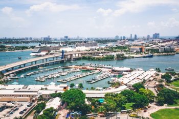 FLHomeBuyers.com, Miami waterfront marina with boats, skyline, and lush greenery, promoting cash home buyers and quick house sales in Florida.