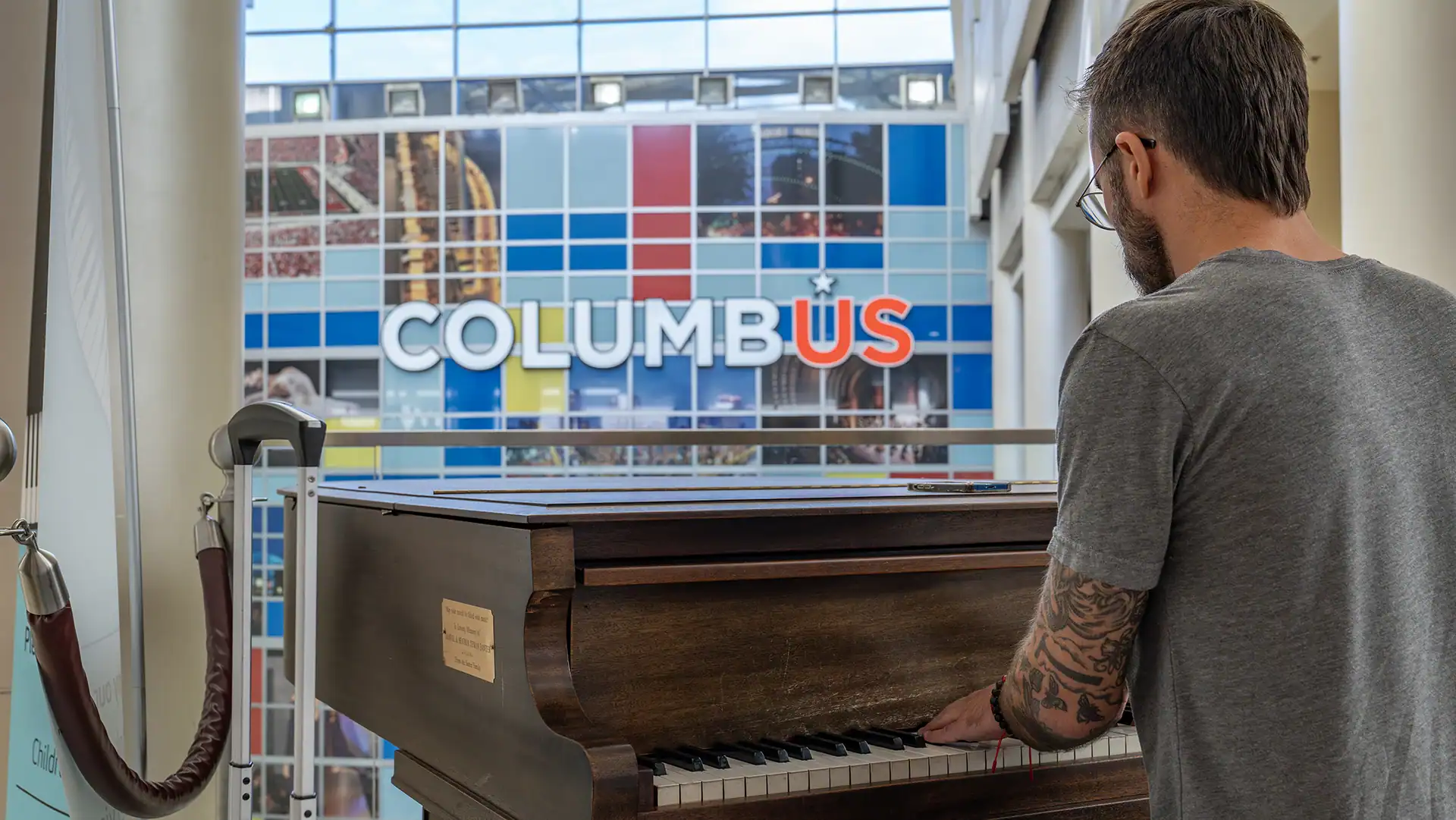 A man playing a piano in front of John Glenn International.