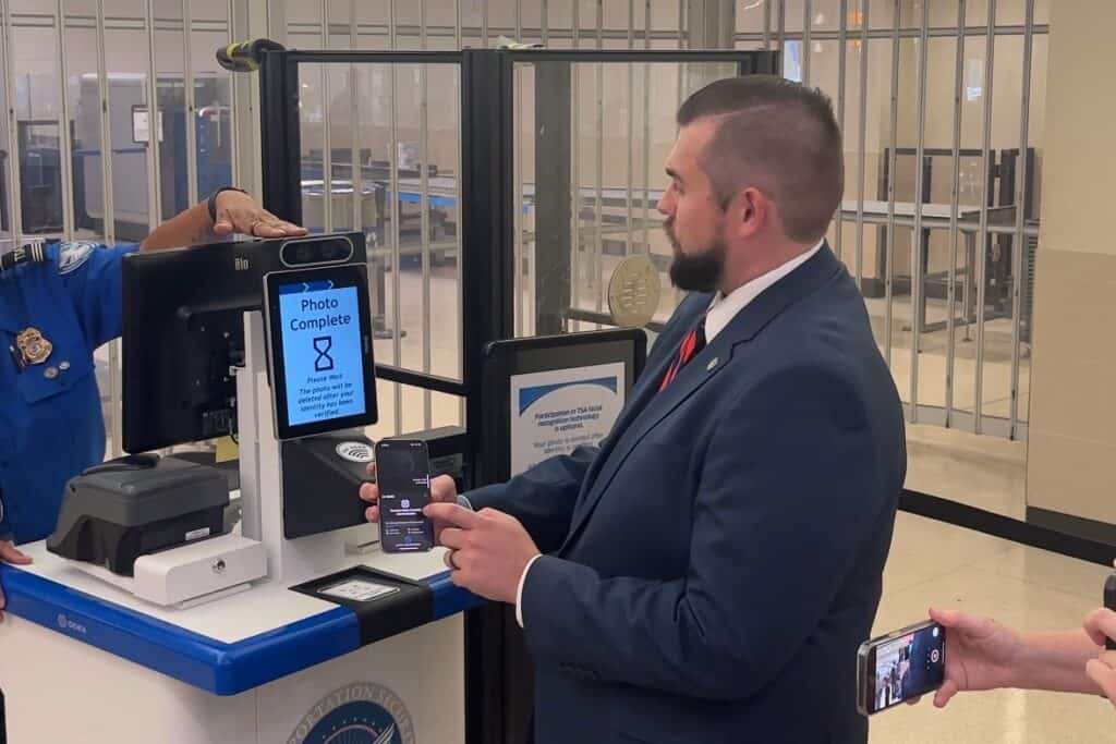 A government worker stands at a TSA kiosk and uses his mobile identification to pass through the security checkpoint.
