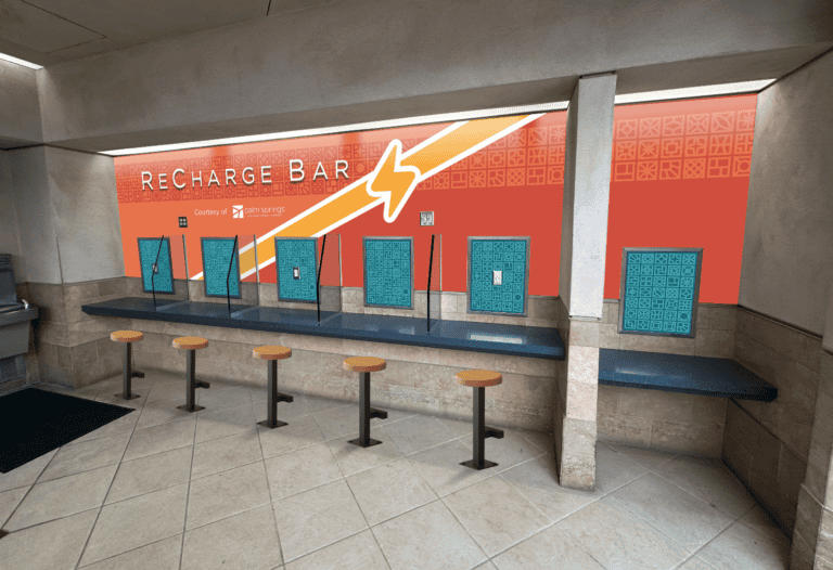 A 'Recharge Bar' at an airport, featuring an orange wall with 'RECHARGE BAR' text, multiple teal charging stations, a dark blue counter, and five wooden stools.