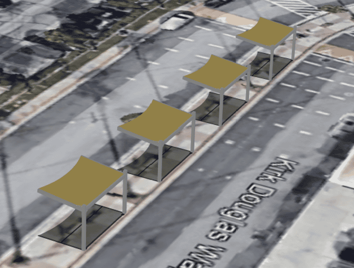 Aerial view of four identical light brown and grey canopy structures lined up along a grey asphalt road with 'Kirk Douglas Way' written on it.