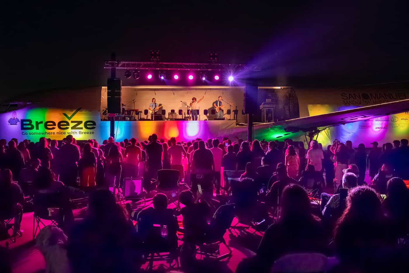 The crowd in front of the Plane Stage under purple and green lighting.