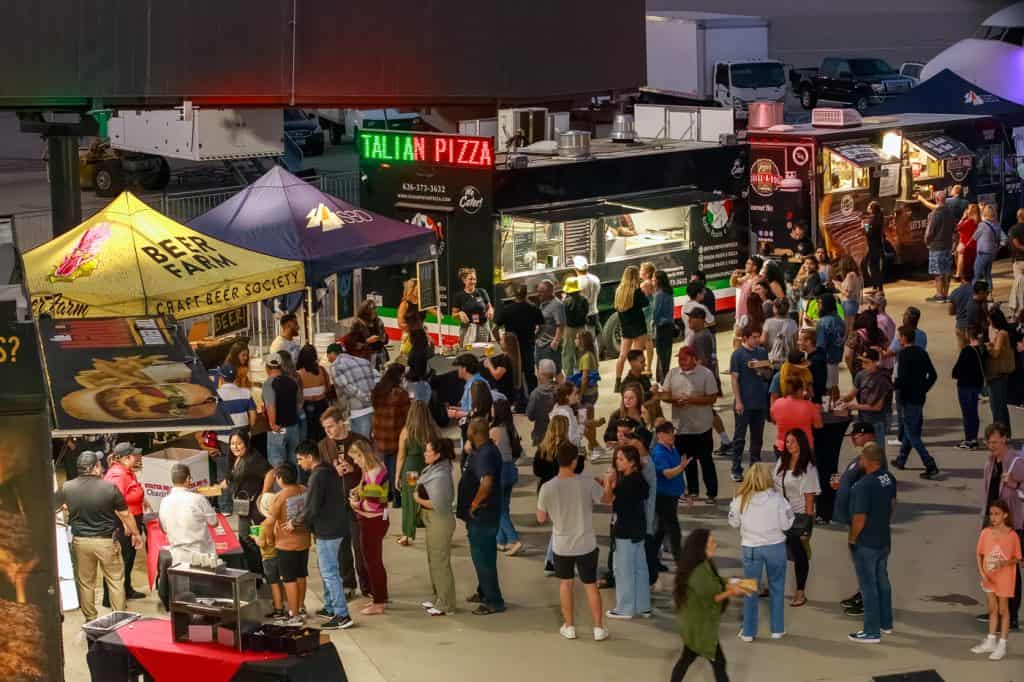 Attendees browsing food trucks and vendor tents after dark.