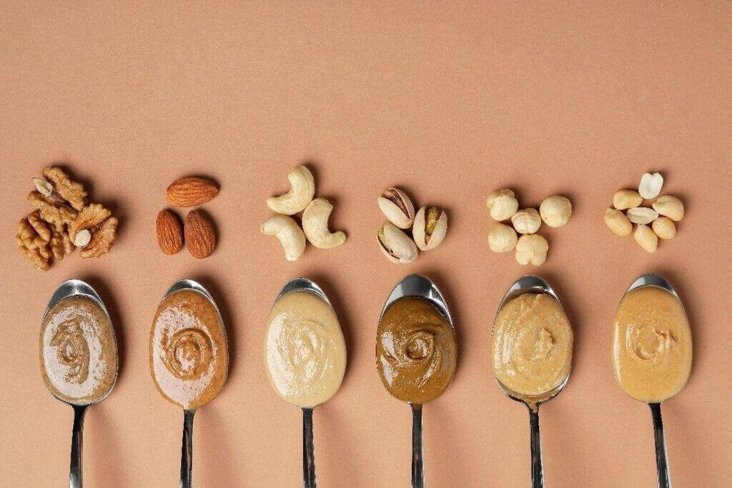 Nut and seed butters with various nuts and seeds on spoons, highlighting their nutritional content a.
