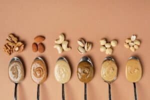 Nut and seed butters with various nuts and seeds on spoons, highlighting their nutritional content a.