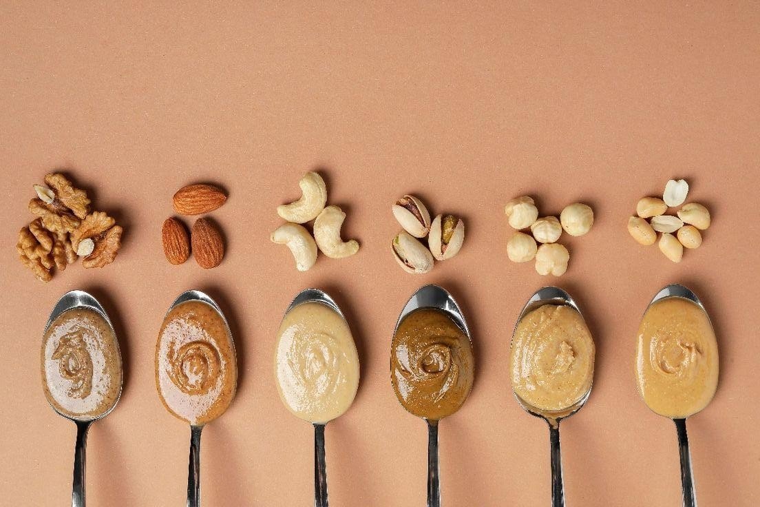 Nut and seed butters with various nuts and seeds on spoons, highlighting their nutritional content a.