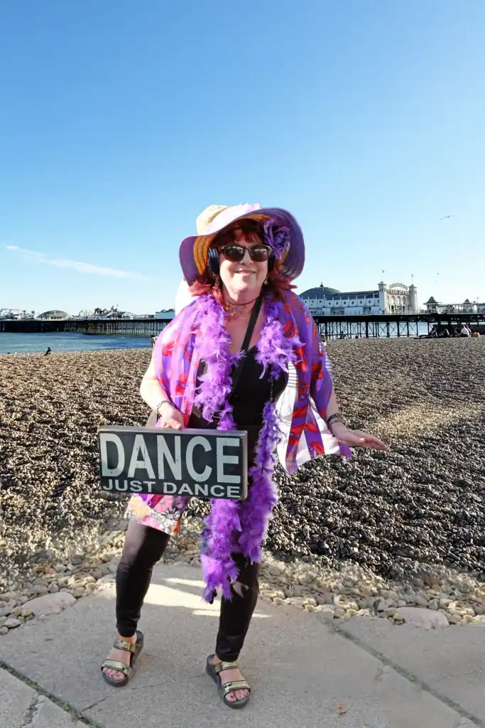 Woman enjoying a silent disco on the beach with headphones and colourful accessories.