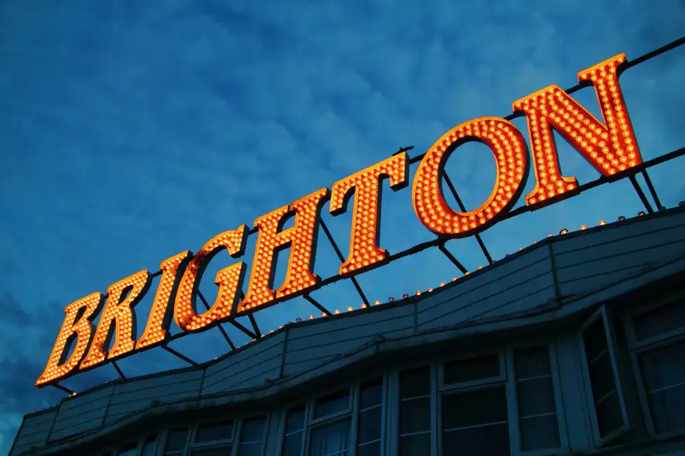 Brighton silent disco sign illuminated at dusk, promoting a fun and unique music experience.