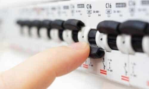 A person’s finger is flipping a black circuit breaker switch on an electrical panel with multiple switches labeled “C16,” similar to those found in modern fuse boxes.