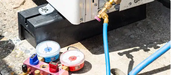 HVAC manifold gauges and hoses connected to an outdoor air conditioning unit during a maintenance or repair procedure.