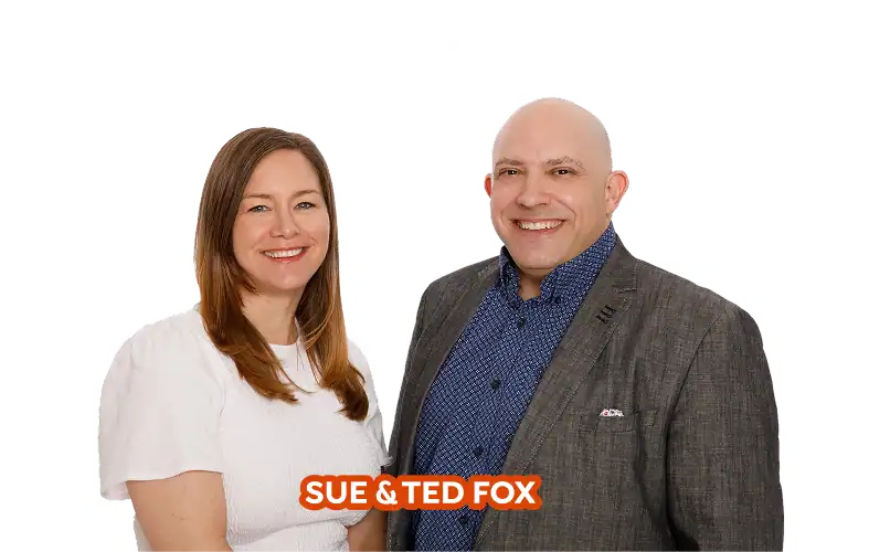 A woman in a white top and a man in a gray blazer stand side by side, smiling, with the text "SUE & TED FOX" at the bottom.