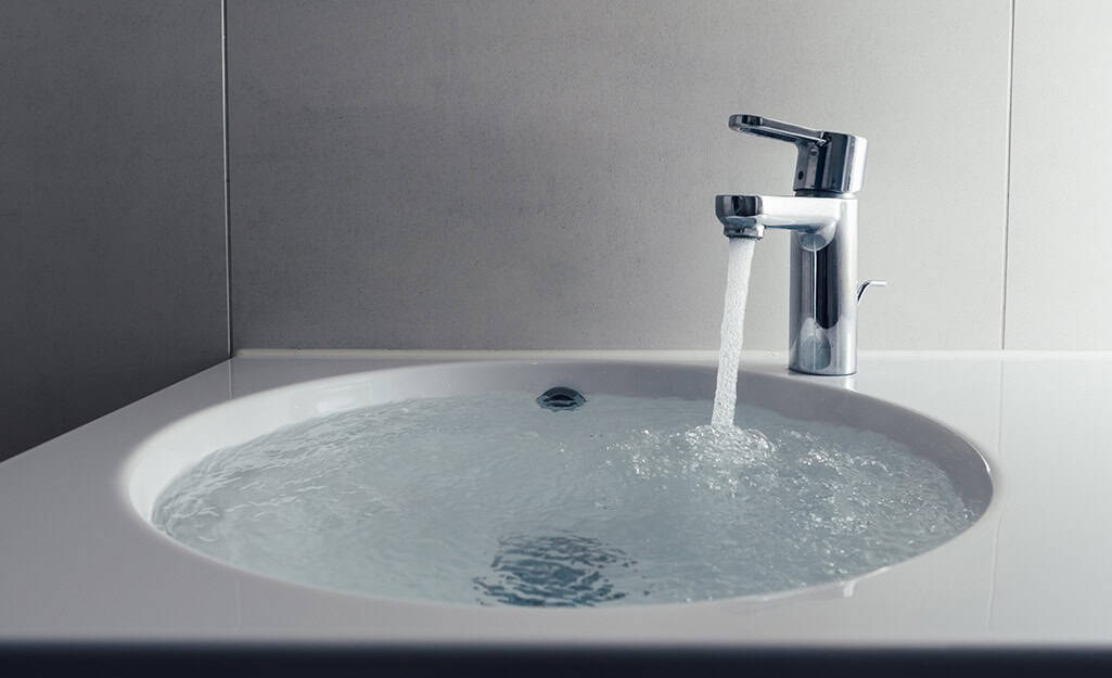 A sink with a modern chrome faucet is running water, filling the basin—a true bathroom plumbing upgrade.