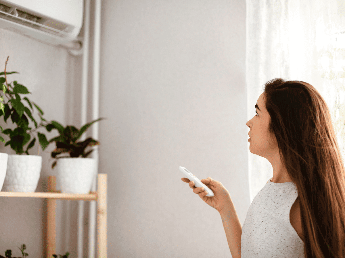 woman controlling mini split air conditioning unit in her home