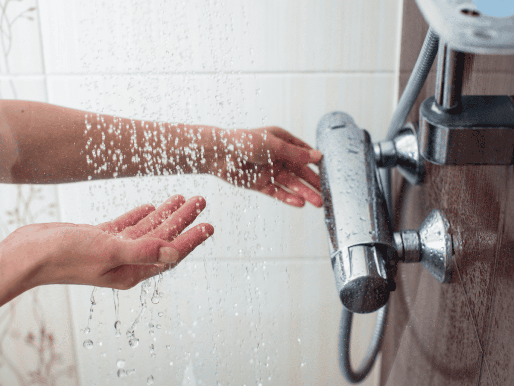 someone running the water in a shower and feeling the temperature of the water