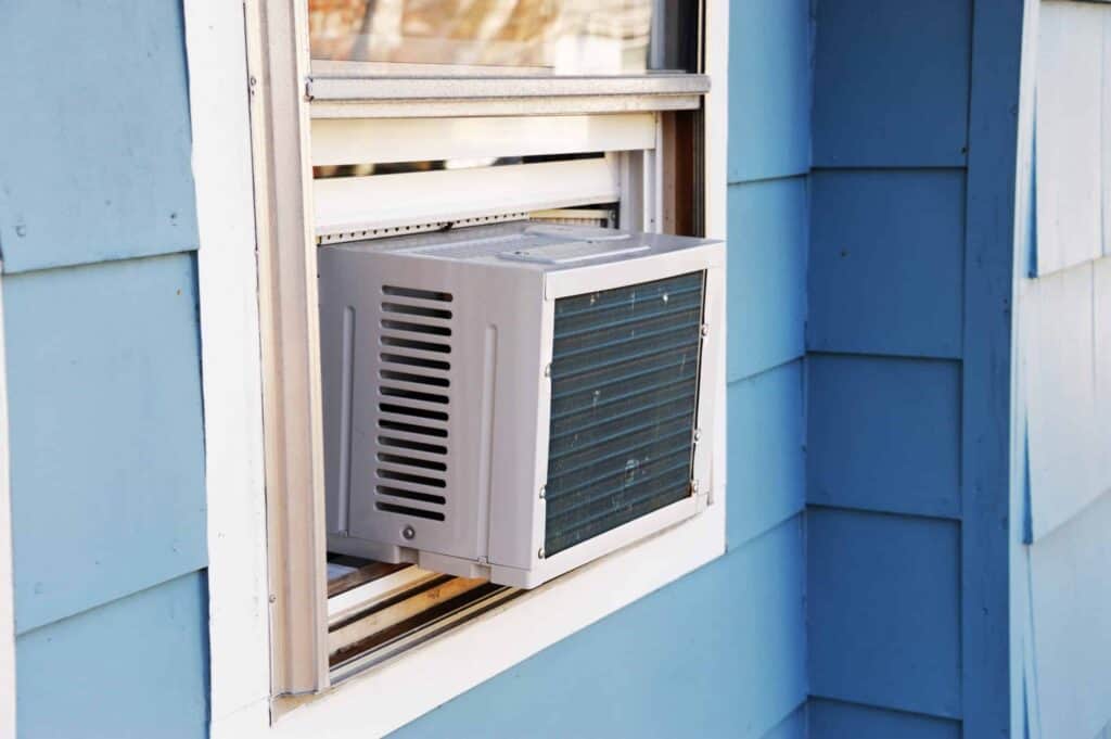 Navigating a summer heatwave becomes manageable with our window air conditioner unit, seamlessly installed in a blue-painted wall. Perfect for those considering AC replacement and essential questions about efficiency and style.