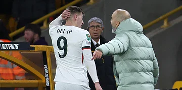 A football player with jersey number 9, Delap, receiving medical attention from a staff member on the sidelines during a match. Other staff and a security personnel are visible in the background.
