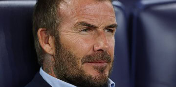 Focused middle-aged man with a beard in a sports stadium, reflecting concentration and determination, ideal for sports, leadership, or motivation keywords.