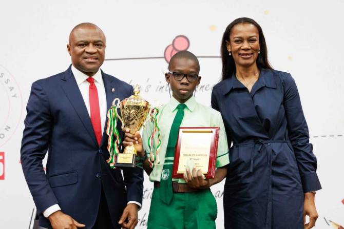 Award-winning student receiving trophy and certificate at a school event with proud officials.