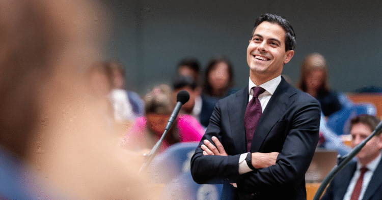 Business professional smiling at a conference or seminar, representing leadership and corporate success, with a diverse audience in the background.