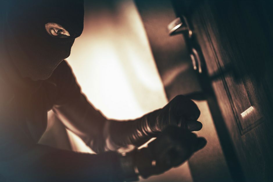 A masked burglar breaking into a drawer, illustrating theft, cybercrime, or security breach. Focus on crime prevention and security awareness.