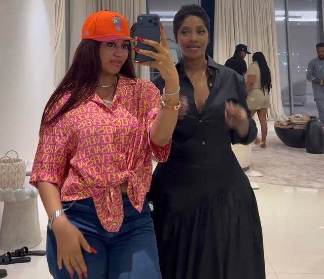 Fashionably dressed women taking a selfie at an indoor social event.