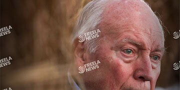 Close-up of an elderly man with white hair and blue eyes, expressing a serious or contemplative mood, featured on Freelanews, a platform for news and updates.