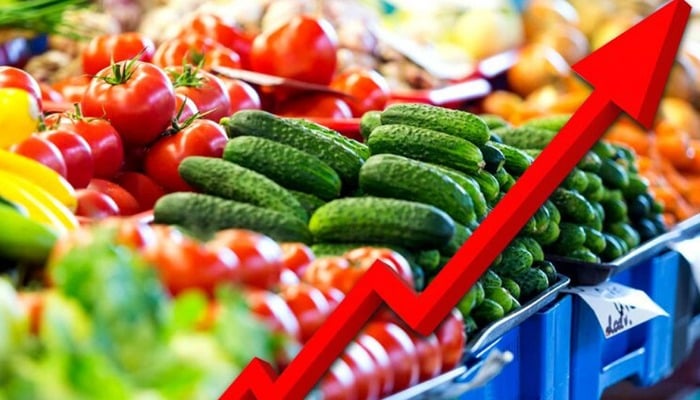 Fresh cucumbers and ripe tomatoes at a market stall with a red upward arrow symbolising growth or increase in produce sales.