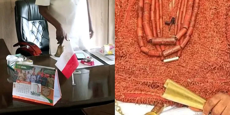 A government official in a white outfit standing in an office with framed photos and emblems on the wall, representing official political or administrative context in Nigeria.