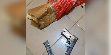 Unsecured firearm and ammunition on tiled floor alongside a torn bread bag, highlighting safety hazards and the importance of gun security in homes.