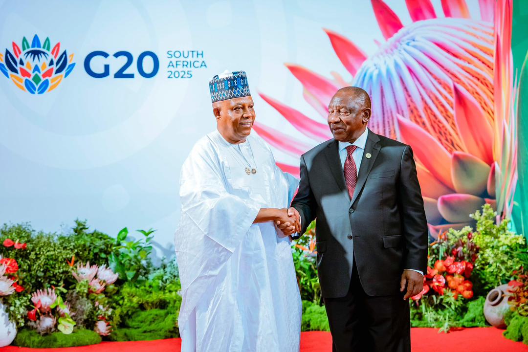 African leaders at G20 South Africa 2025 summit shaking hands in front of floral backdrop.