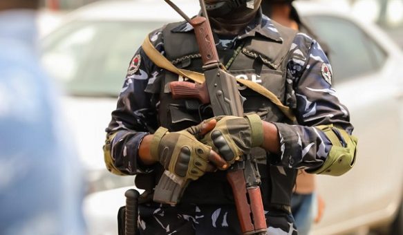 Armed police officer in tactical gear holding a semi-automatic rifle during a security operation in an urban environment.