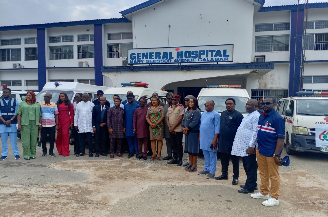 A group of healthcare professionals and officials standing outside General Hospital, Calabar, Nigeria, for an official event or visit, with ambulances and hospital building in background.