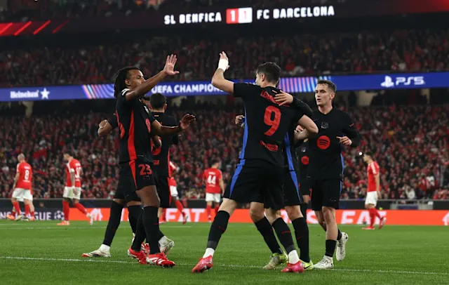 Celebrating FC Barcelona players during a UEFA Champions League match at Estádio José Alvalade, Lisbon. The team shows unity and excitement after scoring against SL Benfica.