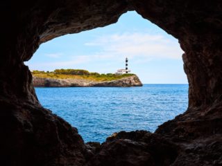 Portocolom Lighthouse on a cliff seen from a cave.