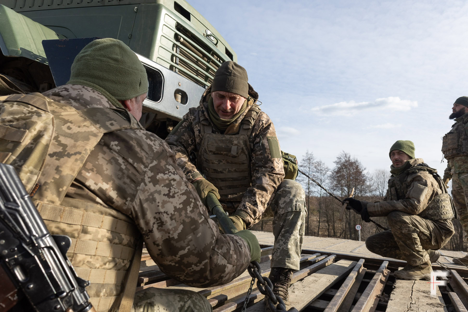 Механіки-водії вчаться закріплювати машини на залізничній платформі.