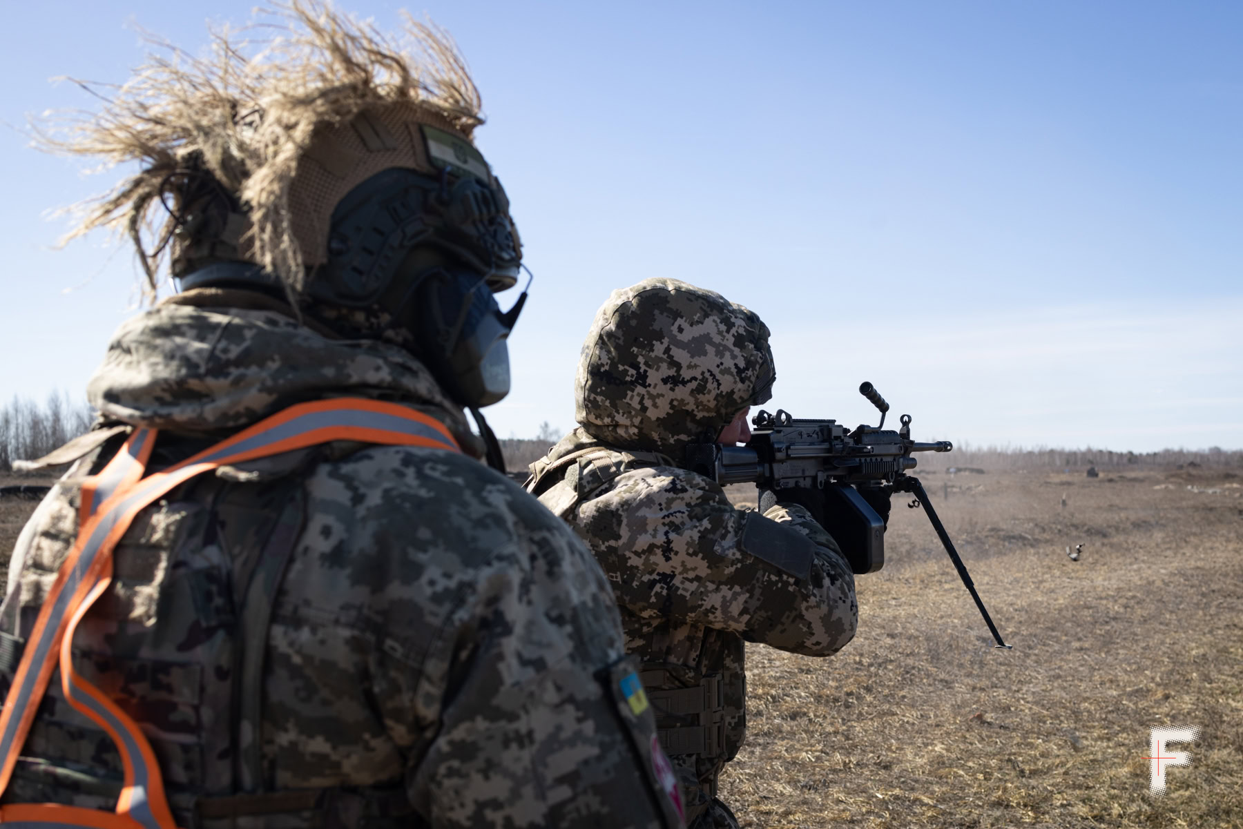 Інструктор спостерігає, як боєць стріляє з американського кулемета М249