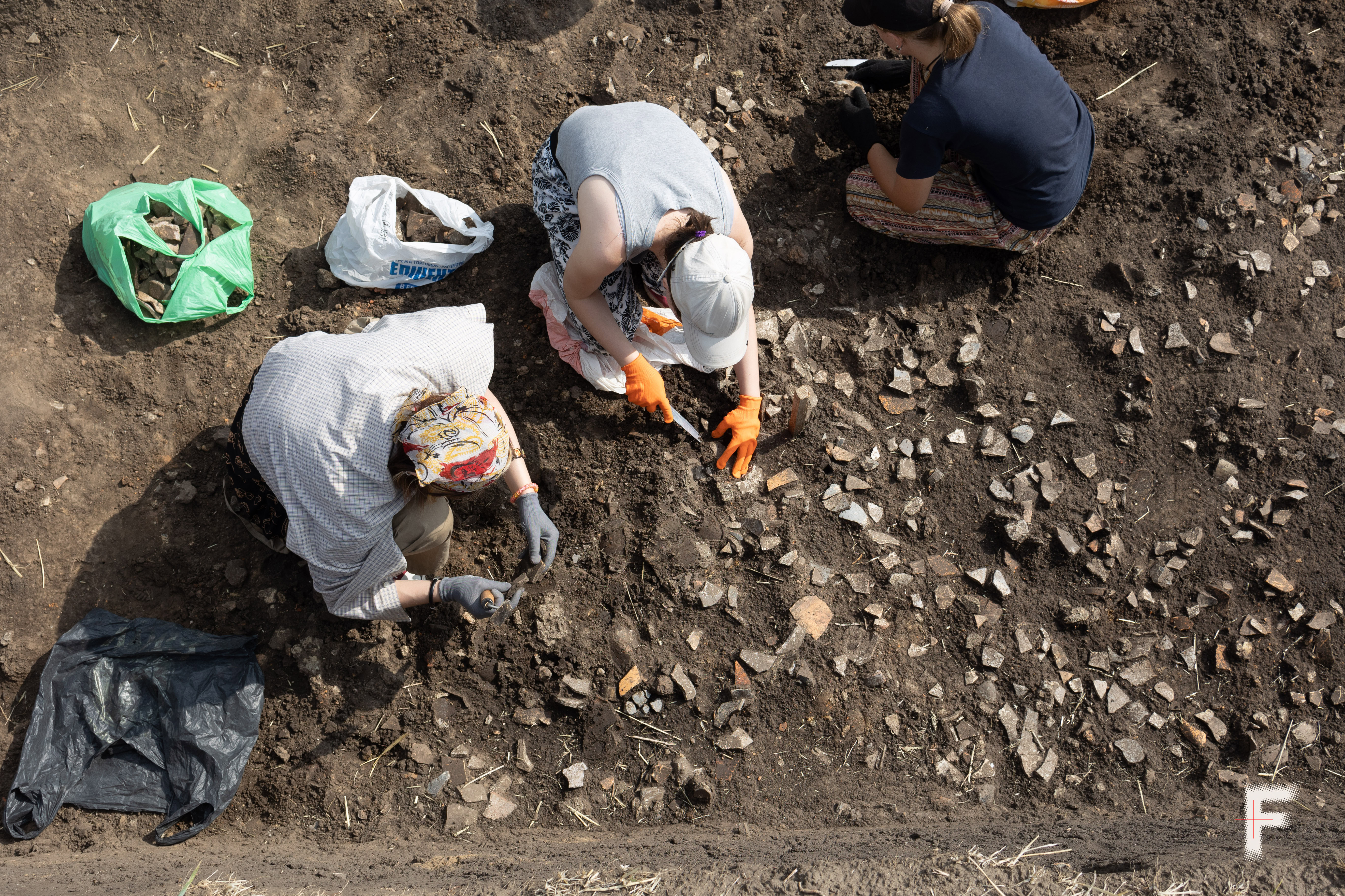 Дівчата обережно розчищають ґрунт у пошуках археологічних знахідок під час археологічних розкопок як форми реабілітації для військових і ветеранів, село Легедзине, Черкаська область, Україна, 22 липня 2025 року. Дубчак Данило / Frontliner