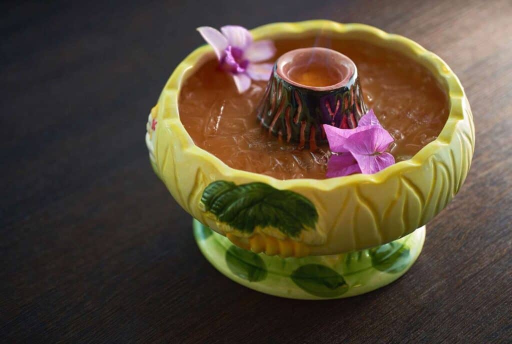 Tropical drink in decorative bowl with flowers.