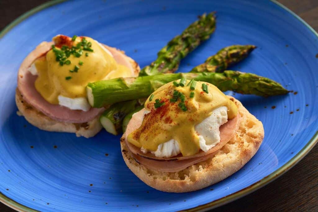 Eggs Benedict with asparagus on blue plate.