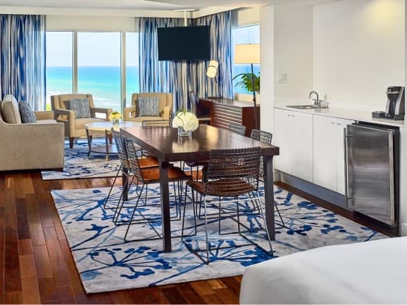 Hotel guestroom seating area and a dining area with an ocean view.