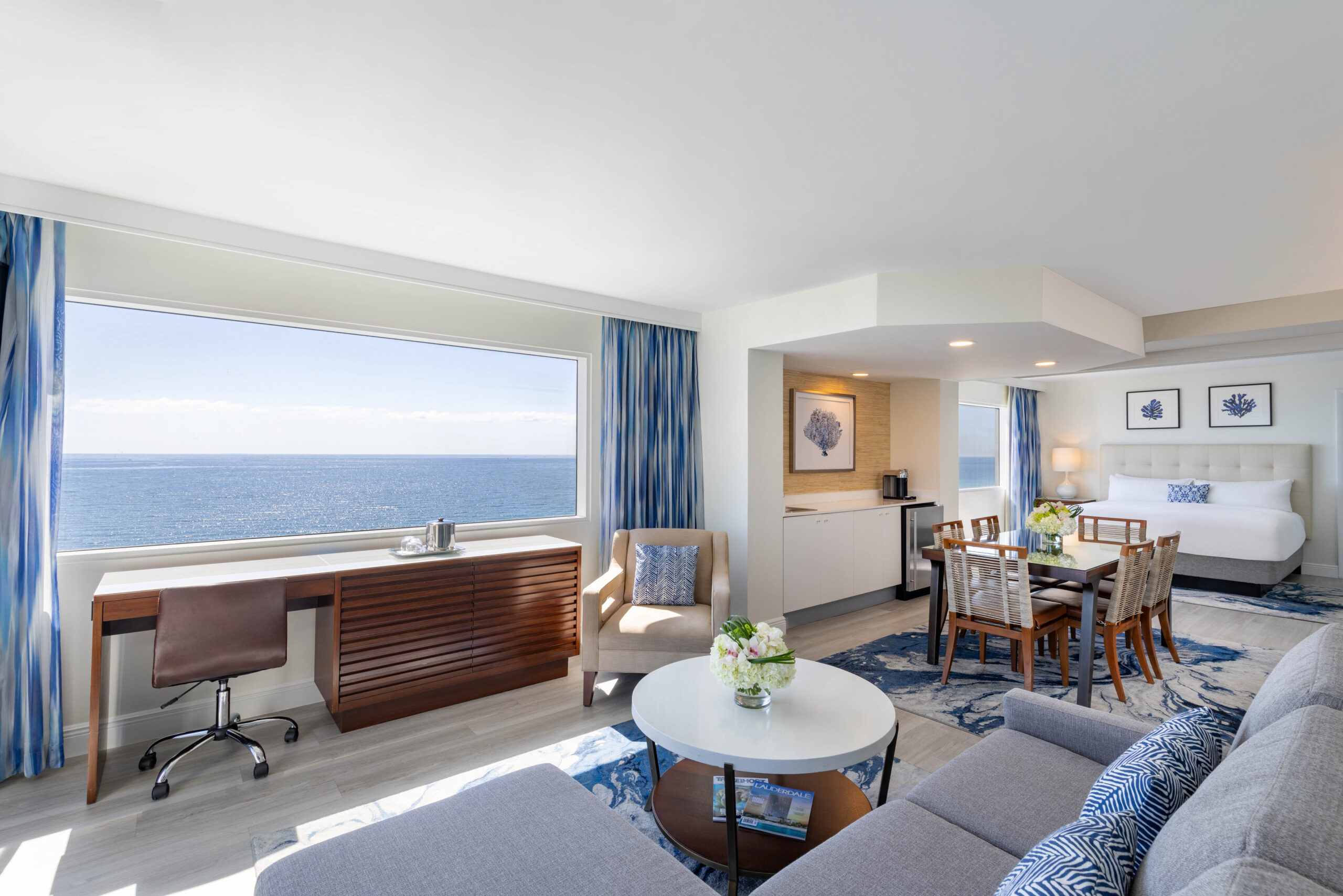 A luxurious suite featuring large windows with a stunning view of the ocean and coastline.