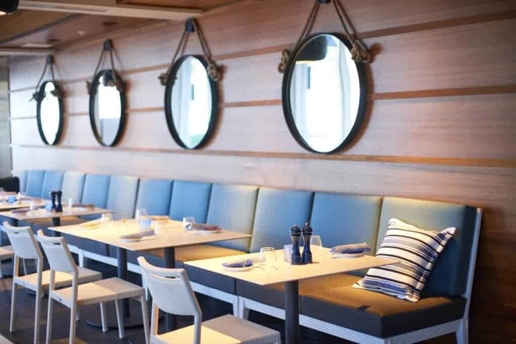 Cozy restaurant seating with nautical mirrors on wall.