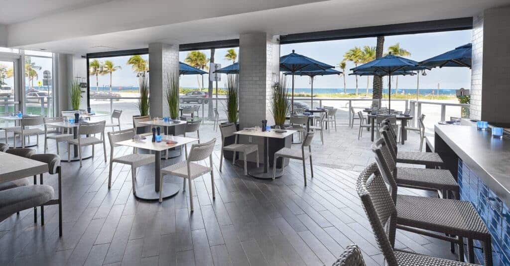 Open-air dining with ocean view and patio umbrellas.