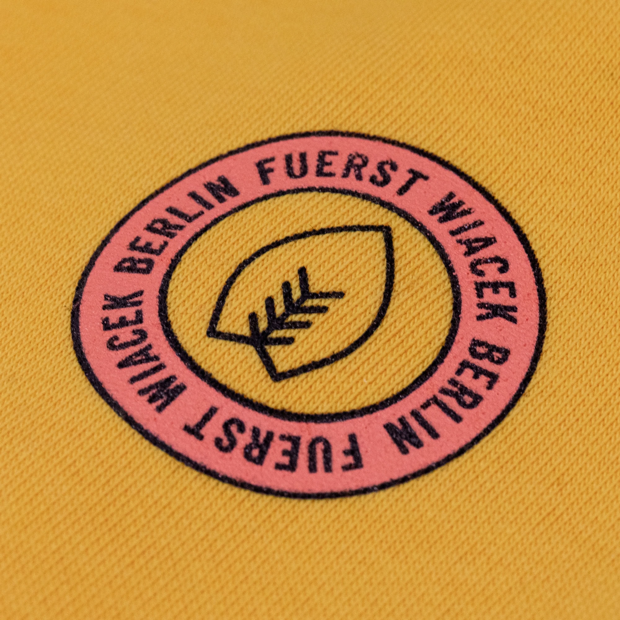 Vollkornfußball logo embroidered on yellow fabric, representing Fuerst Wiacek Brewery, showcasing craftsmanship and craft beer branding.