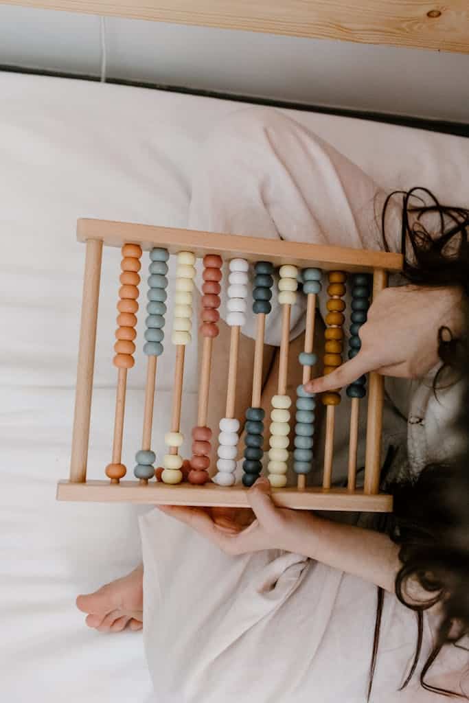 A child playing with a colorful wooden abacus, focusing on math learning and development.