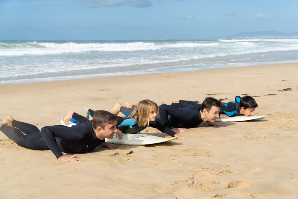 Family enjoying a surf lesson on the beach in Portugal, practicing on the sand.